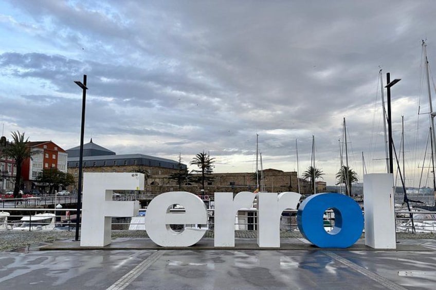 Un puerto deportivo con barcos, una noria grande y un edificio histórico al fondo. 4
