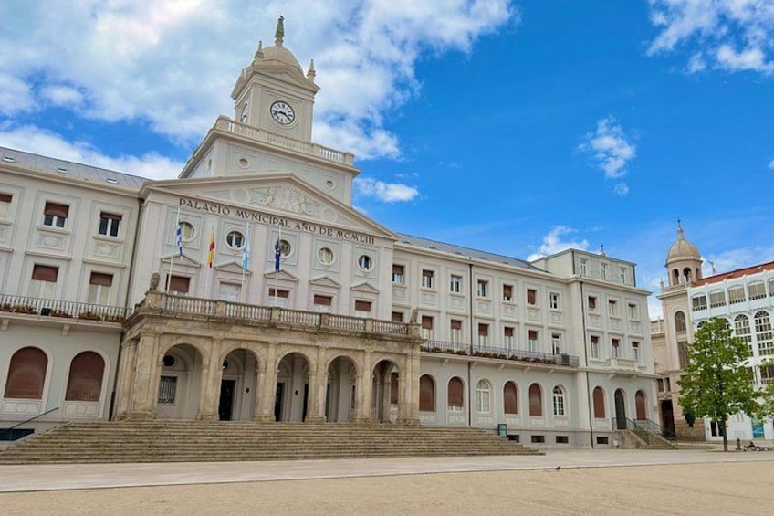 Un gran edificio blanco con una torre de reloj, ventanas en arco y una entrada central. 5