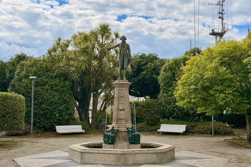 Una estatua sobre un pedestal en un parque con bancos y árboles. 3