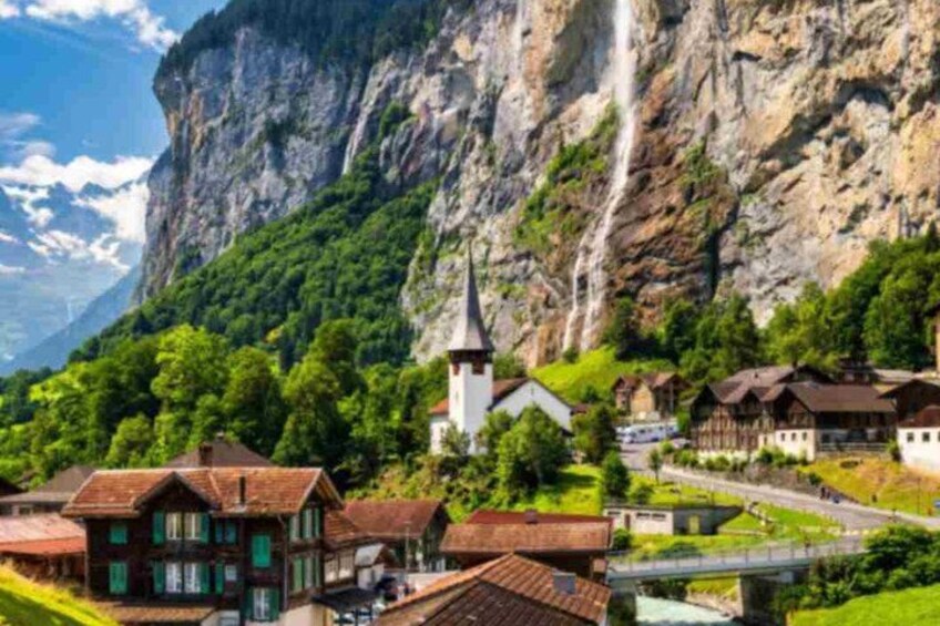 A mountainous village with traditional houses, a church, and a waterfall. 3