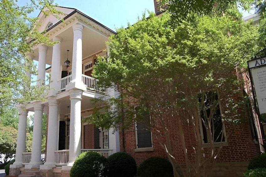 A two-story brick house with a white porch and columns. 2