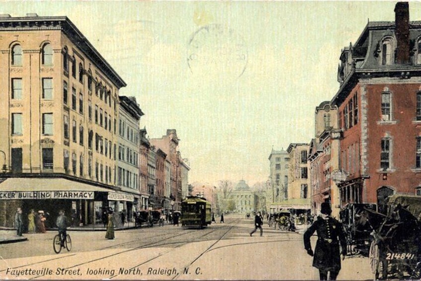 A street scene with buildings, a horse-drawn carriage, and a bicycle. 2