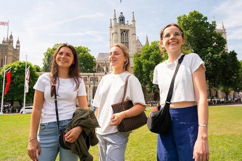 Drie personen staan in een grasveld, met een historisch gebouw op de achtergrond. 4