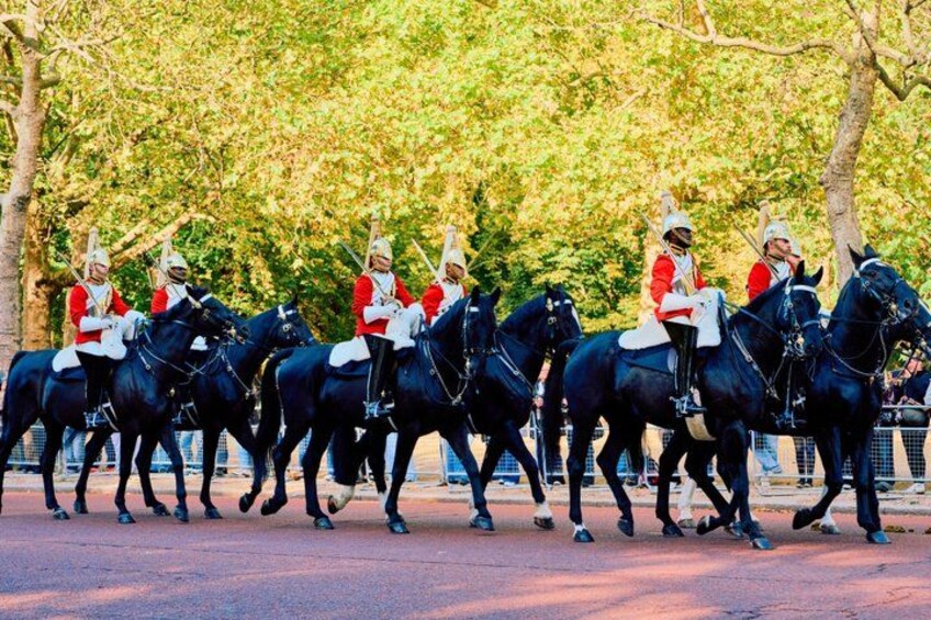 Un grupo de guardias a caballo con uniformes rojos y cascos blancos, montados en caballos negros en fila. 5