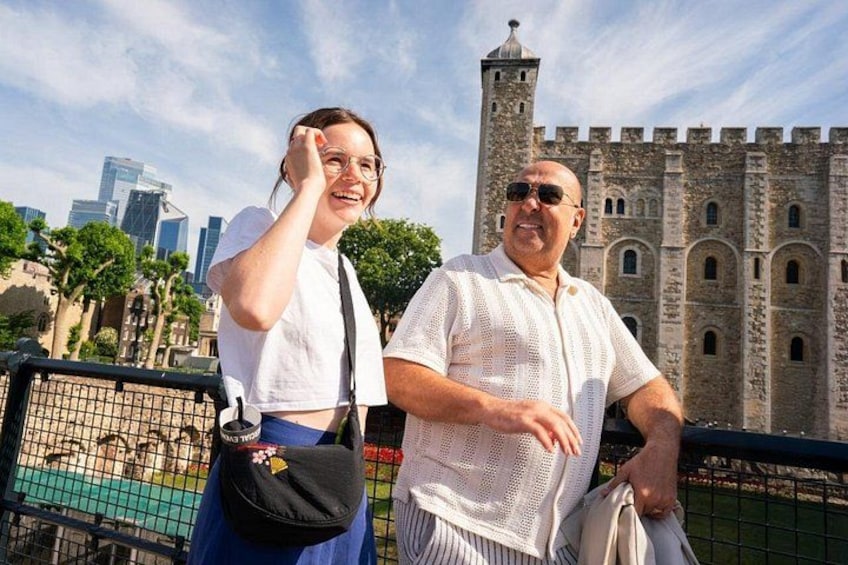 Twee personen staan voor een historisch kasteel, met een moderne stadsachtergrond. 3