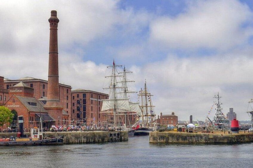 Een haven met hoge schepen, een bakstenen gebouw en een vuurtoren. 3