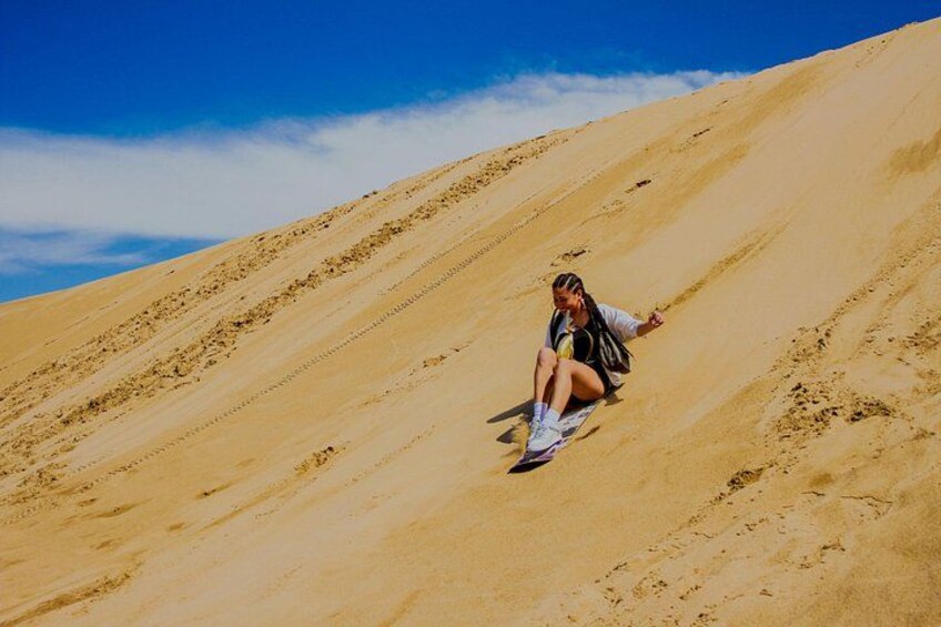 Una persona sentada en una duna de arena bajo un cielo azul despejado. 4