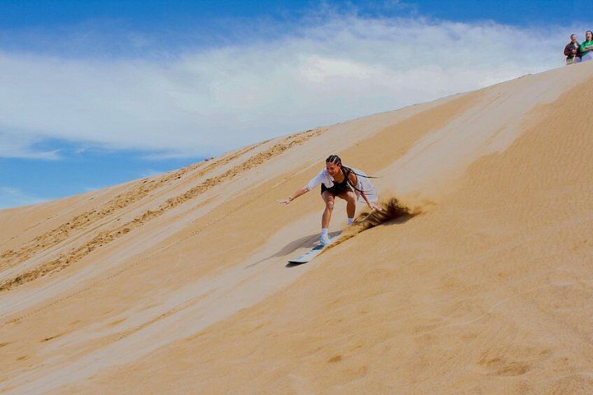 Una persona deslizándose por una duna de arena. 1