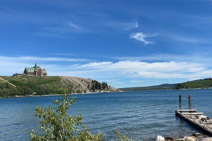 A lake with a house on a hill, a dock, and a clear sky. 2