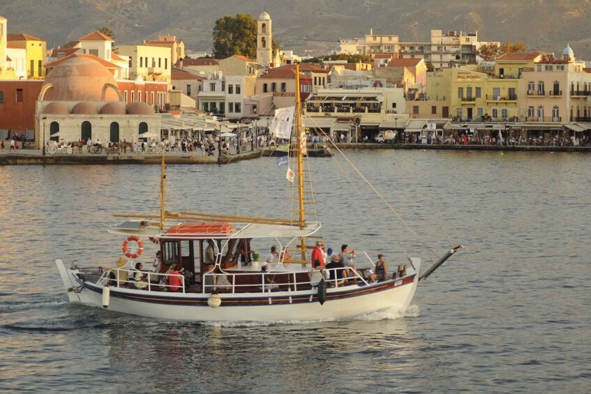 A boat with passengers on a calm body of water, surrounded by a coastal town with buildings and a church. 1