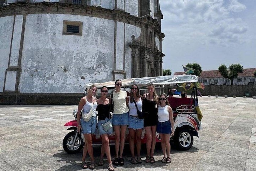Un grupo de personas posa frente a un edificio histórico con un coche antiguo estacionado cerca. 5