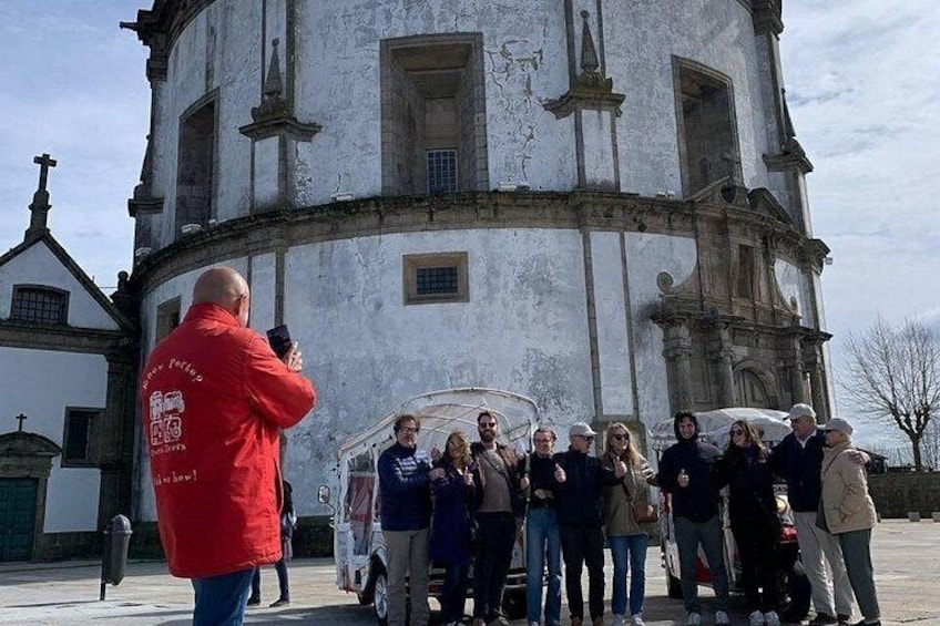 Un grupo de personas frente a un edificio histórico con un campanario. 4