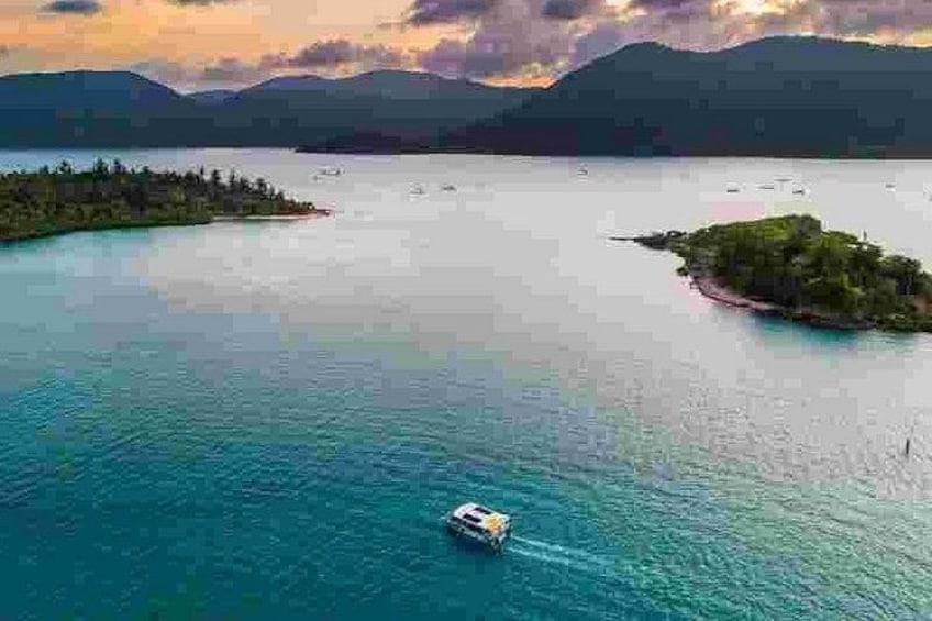 A boat on a calm lake surrounded by islands and mountains. 3