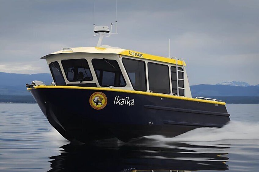 Un bateau nommé « Ikaita » sur une étendue d’eau calme, avec des montagnes en arrière-plan. 2