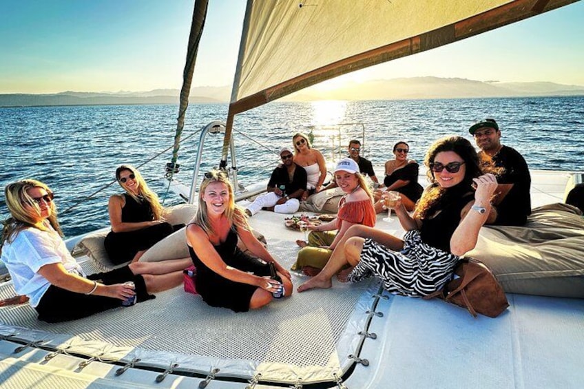 Een groep mensen op een zeilboot, met een helder uitzicht op zee en verre bergen. 2