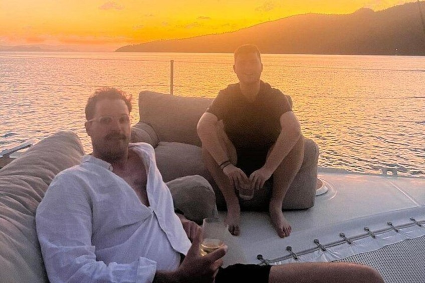Twee personen zitten in een boot, met een zonsondergang op de achtergrond. 4