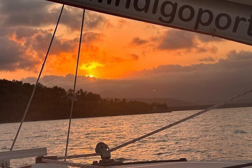 Een zonsondergang boven een wateroppervlak met een zeilboot. 3