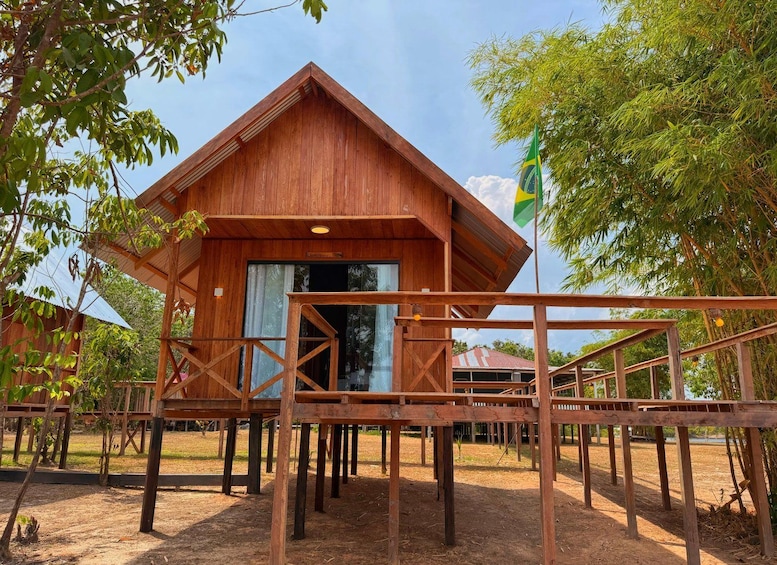A wooden cabin with a balcony, surrounded by trees and a clear sky. 1