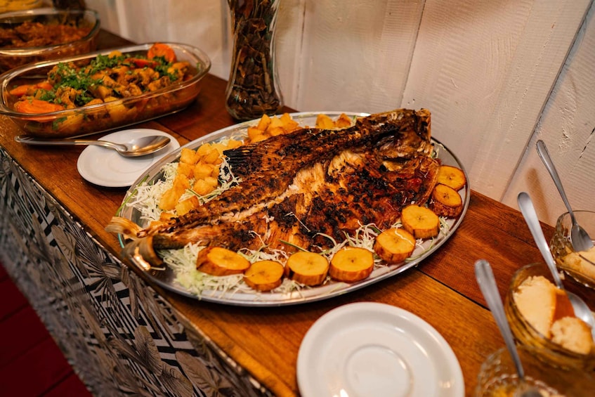 A large grilled fish on a plate with sliced potatoes and garnished with herbs. 5