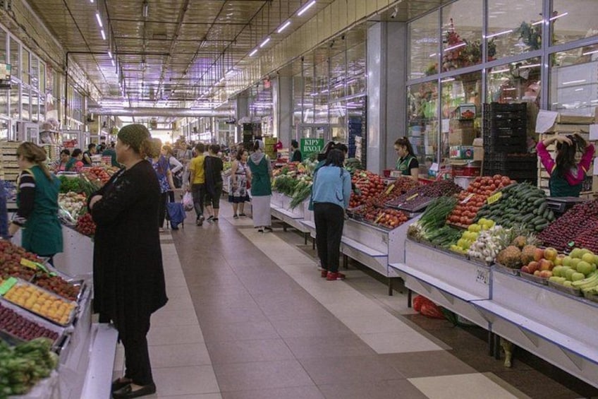A grocery store with shoppers and produce displays. 2