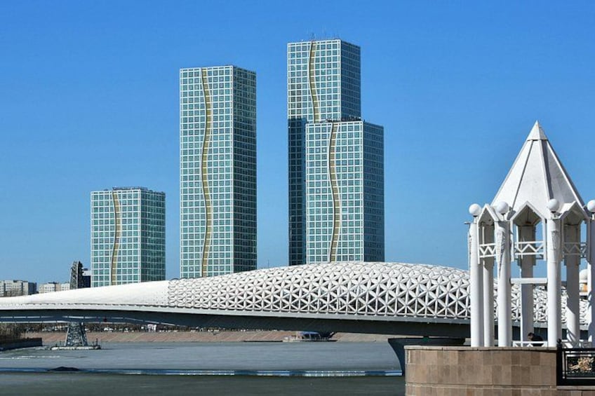 A modern bridge with a unique geometric design, a river, and three tall skyscrapers with a distinctive facade. 5