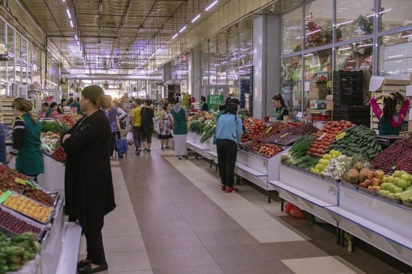 An indoor market with people shopping and vendors selling produce. 2