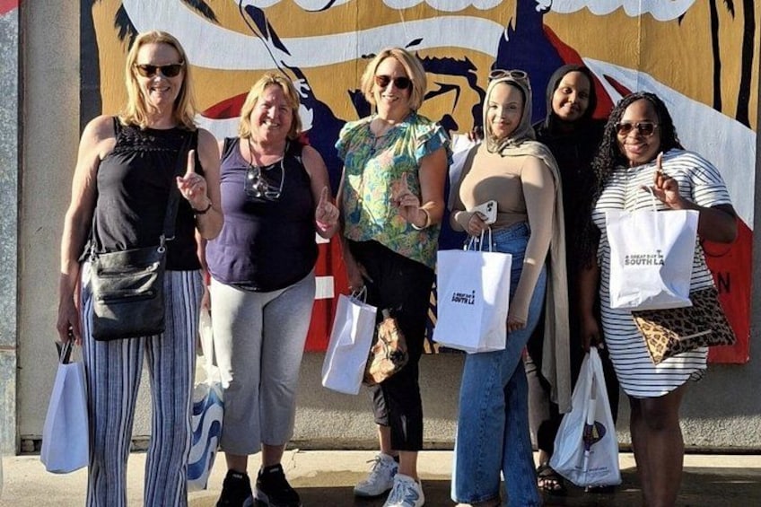 A group of people standing in front of a mural with a flag. 2