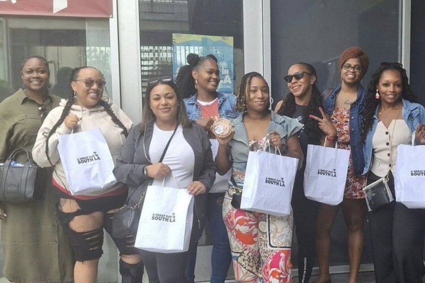 A group of people standing outside a building, holding shopping bags with a logo. 3