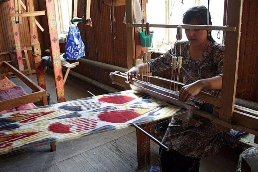 Una persona tejiendo en un telar con tela colorida. 1