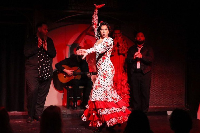 A woman in a red and white dress performing on stage with a guitar player in the background. 3