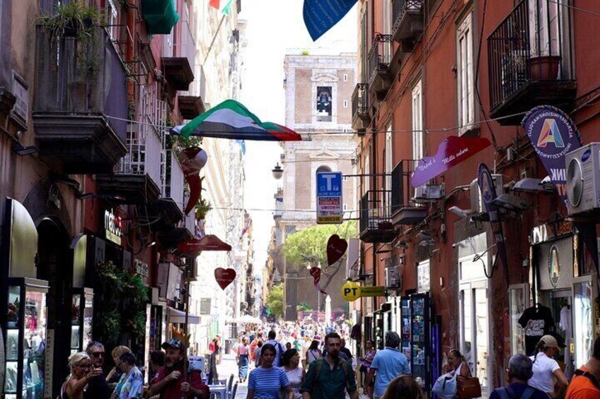 A crowded street with people walking, shops, and hanging decorations. 4