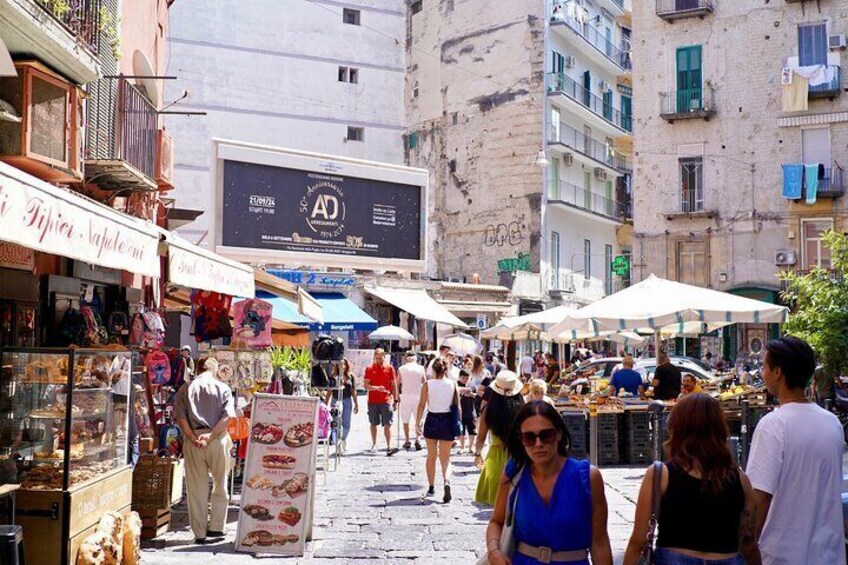 A bustling outdoor market with people shopping and vendors selling goods. 3