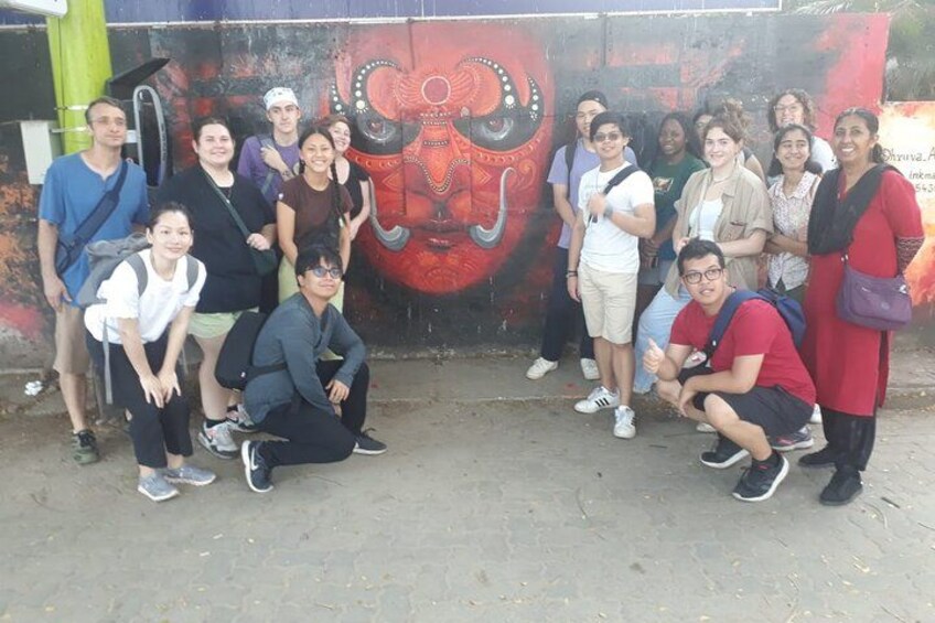 Een groep mensen die poseren voor een muurschildering met een groot gezicht. 4