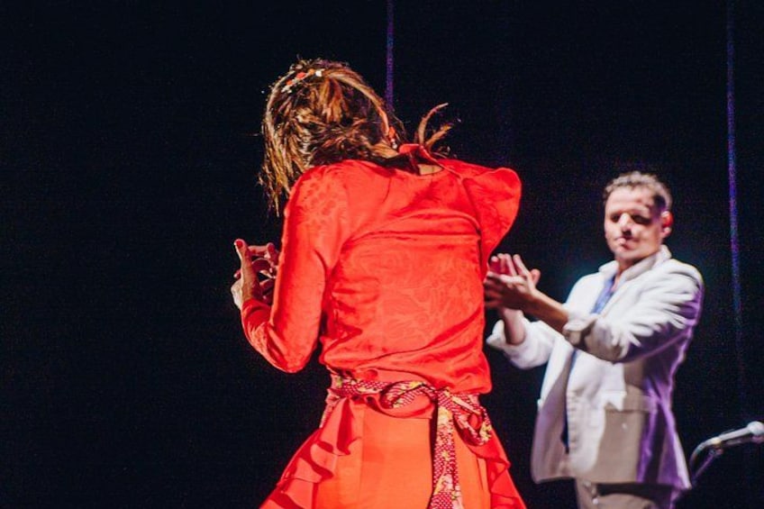 A person in a red dress performing on stage with a microphone stand. 1