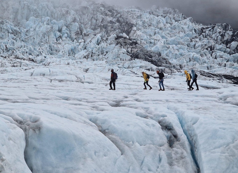 A group of people hiking on a glacier with ice formations in the background. 4