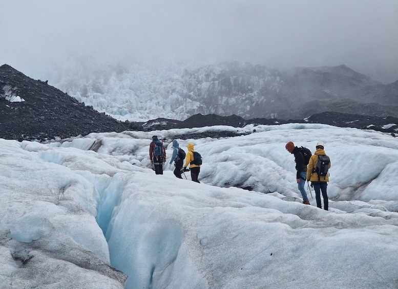 A group of hikers on a glacier with ice formations and mountains in the background. 2