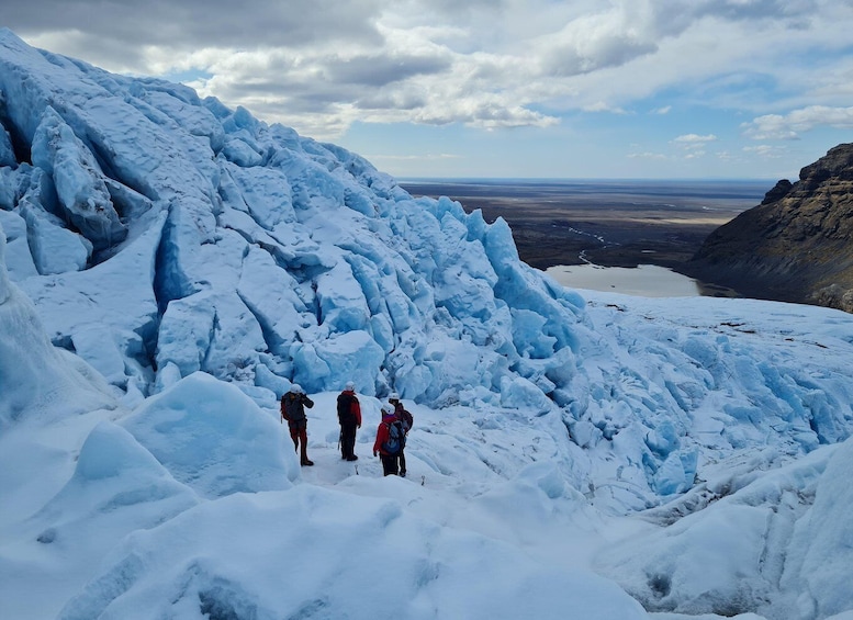 A group of hikers on a snowy mountain with a glacier and a valley in the background. 1