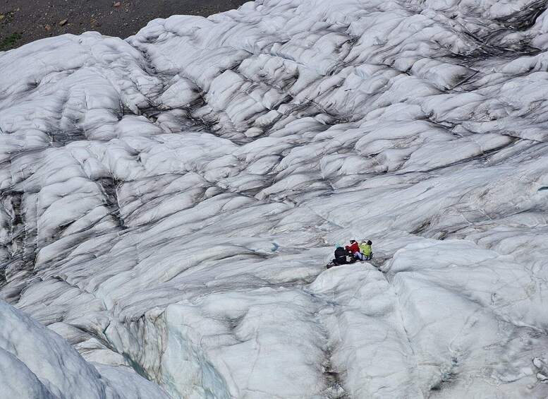 A group of people sitting on a glacier. 3