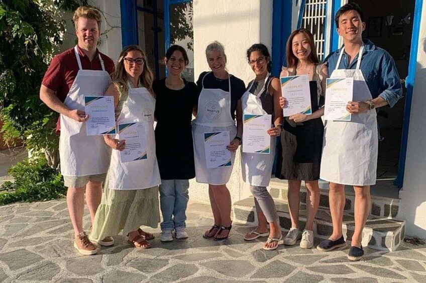 Un grupo de personas sosteniendo certificados frente a un edificio con puertas azules. 2