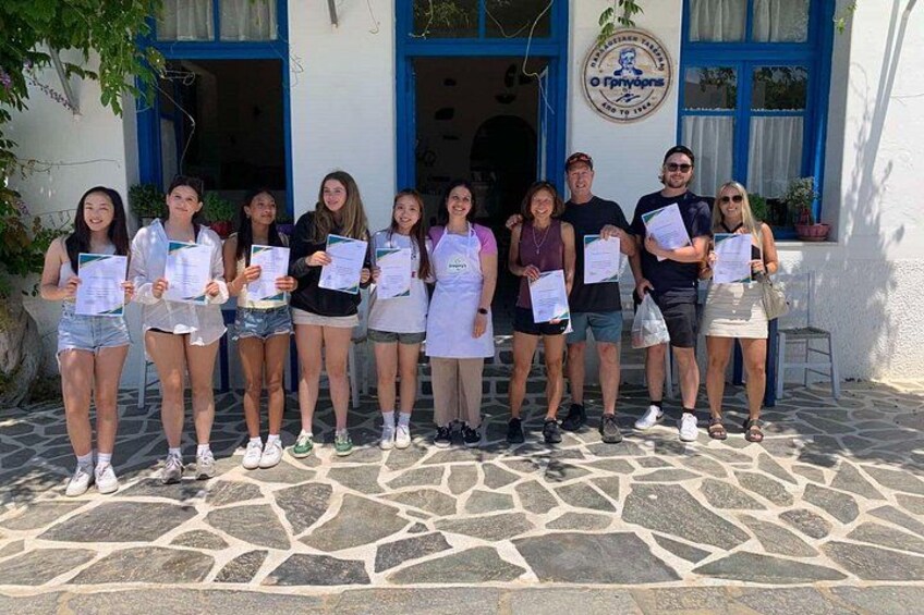 A group of people holding certificates in front of a building with a blue and white facade. 2