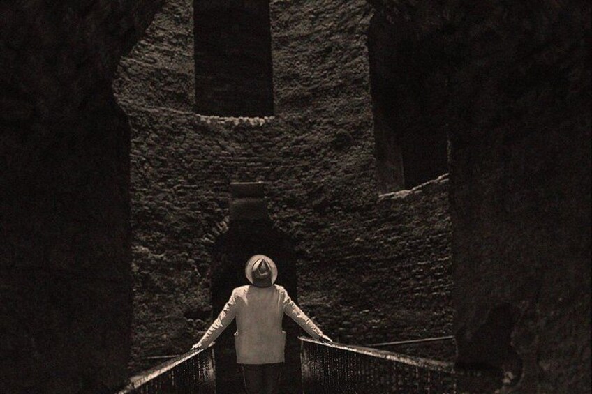 Una persona parada sobre un puente, con un muro de piedra al fondo. 5