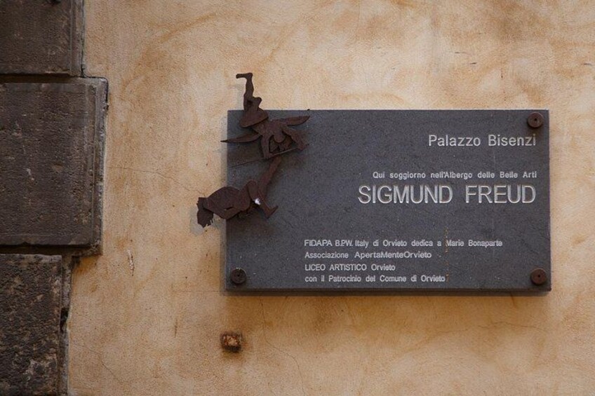 Una placa en una pared con el texto 'Palazzo Bisenzio' y 'SIGMUND FREUD' junto con información adicional sobre una asociación. 1