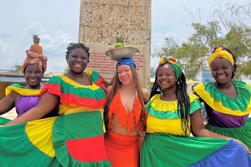 Un groupe de personnes vêtues de costumes traditionnels aux couleurs vives, un monument de pierre et un ciel dégagé. 3