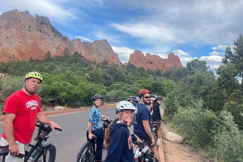 A group of people on bicycles, a red road, and red rock formations in the background. 5