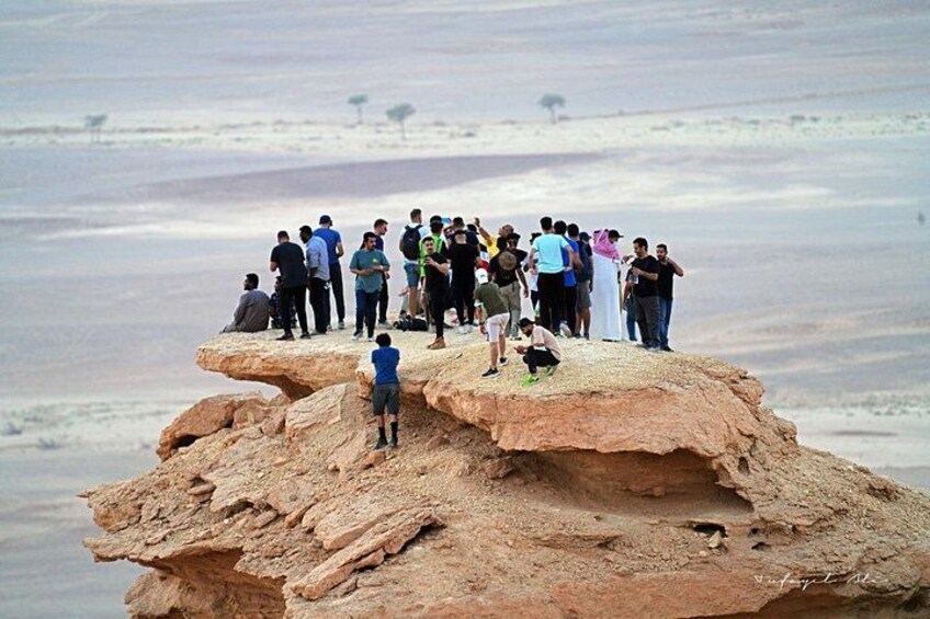 Un groupe de personnes se tient debout sur une formation rocheuse, dans un paysage désertique. 2