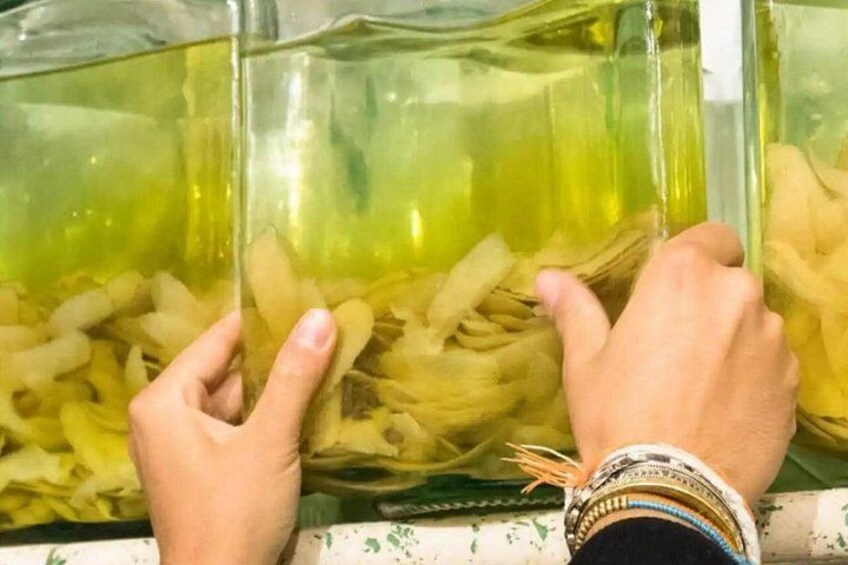 Mani che tengono un contenitore trasparente riempito con un liquido giallastro e alcuni oggetti bianchi. 4
