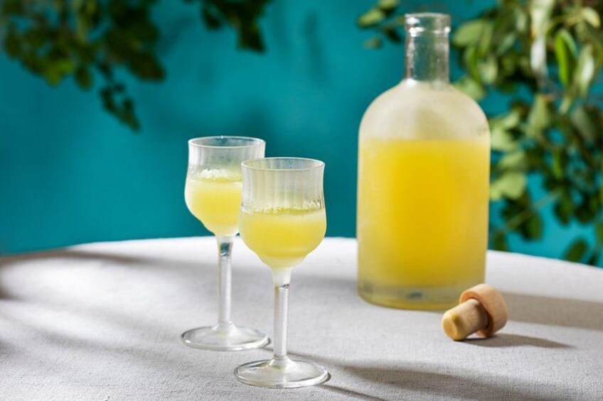 Due bicchieri di bevanda gialla su un tavolo, con una bottiglia di liquido giallo sullo sfondo. 5