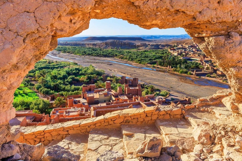 A view through a rock arch of a river valley with terraced fields and a settlement. 4