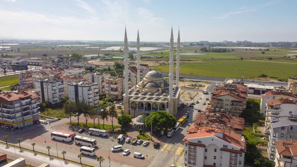 A mosque with four minarets, surrounded by residential buildings and a highway. 4