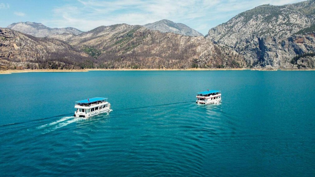 Two boats on a calm lake with mountains in the background. 1